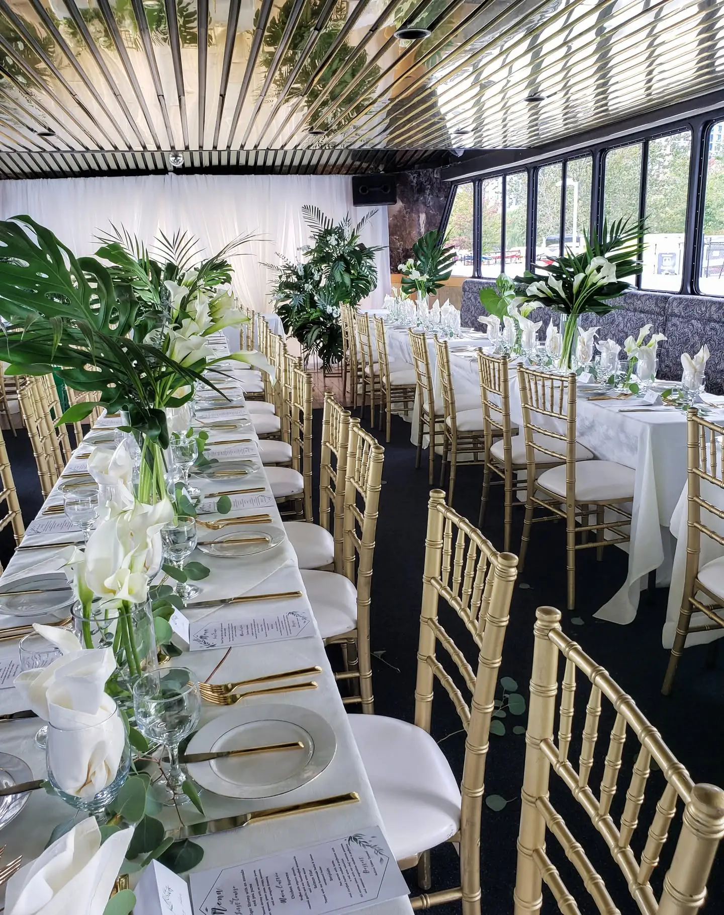 Formal dining tables set with white florals and gold chairs aboard Yankee Lady